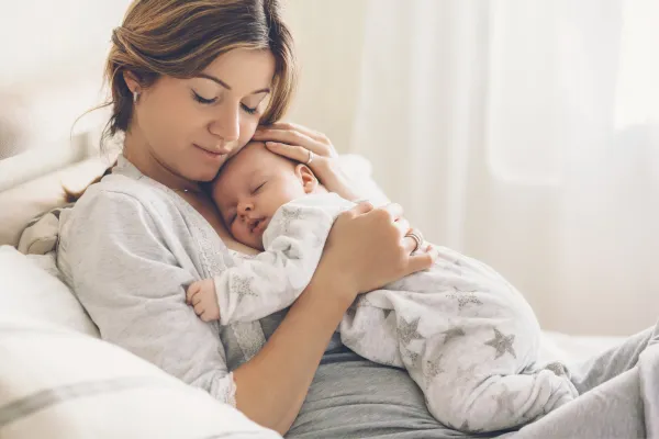 A tired mom snuggling her newborn